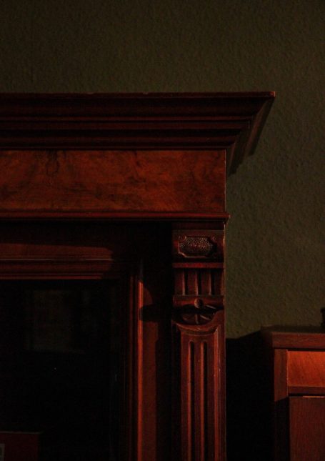 Antiker dunkler Schrank vor tiefgrüner Wand – stimmungsvolle Herbstfotografie mit nostalgischer Atmosphäre.