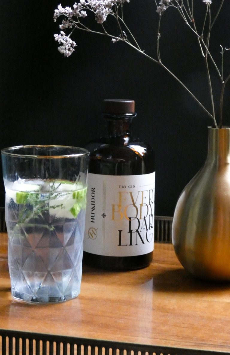 Elegante Gin-Inszenierung mit Glas und weißen Blüten – stilvolle Produktfotografie mit moody Lichtstimmung.