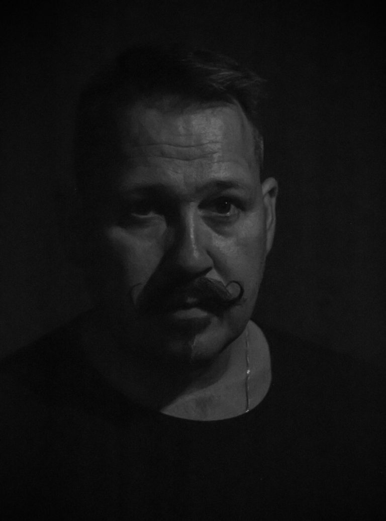 Dramatisches Schwarz-Weiß-Porträt – Charakter & Tiefe Schwarz-Weiß-Charakterporträt eines Mannes mit Moustache – geheimnisvolle Licht-Schatten-Wirkung, dunkler Hintergrund, intensiver Ausdruck.