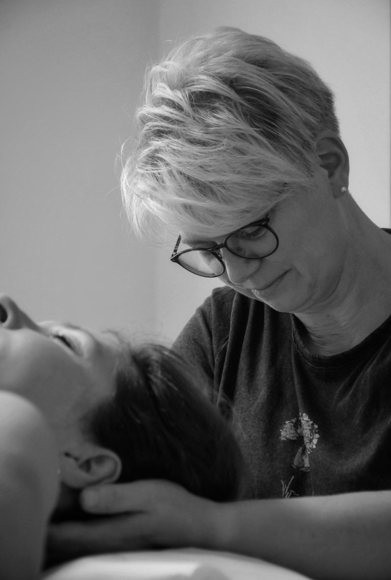 Geschäftsfotografie in einer Osteopathie-Praxis – Therapeutin arbeitet mit einer liegenden Klientin, vertrauensvolle Atmosphäre.